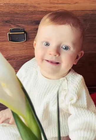 Виктория с любопытством рассматривает цветок. ФОТО: соцсети